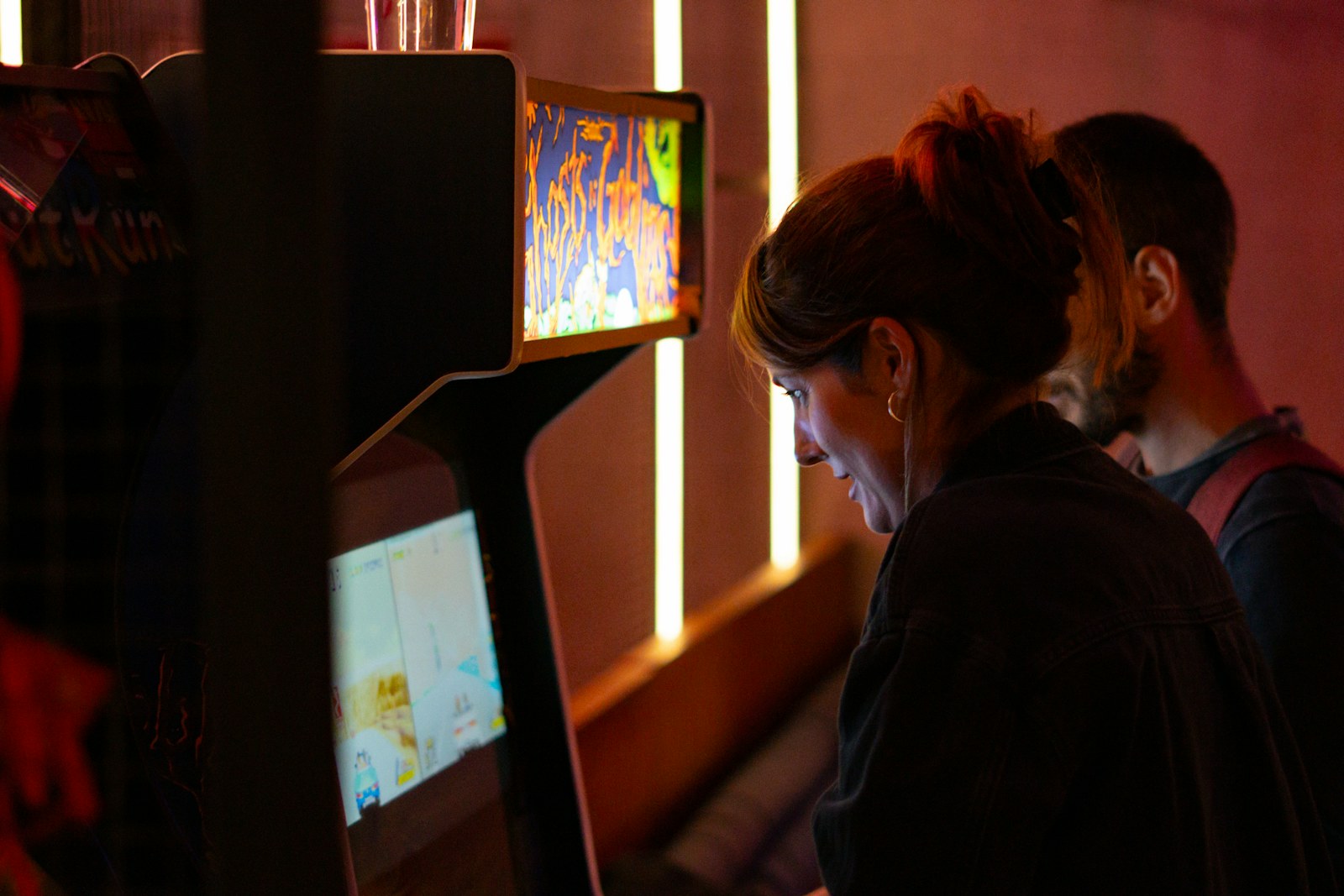 Couple playing arcade games together in a dimly lit room