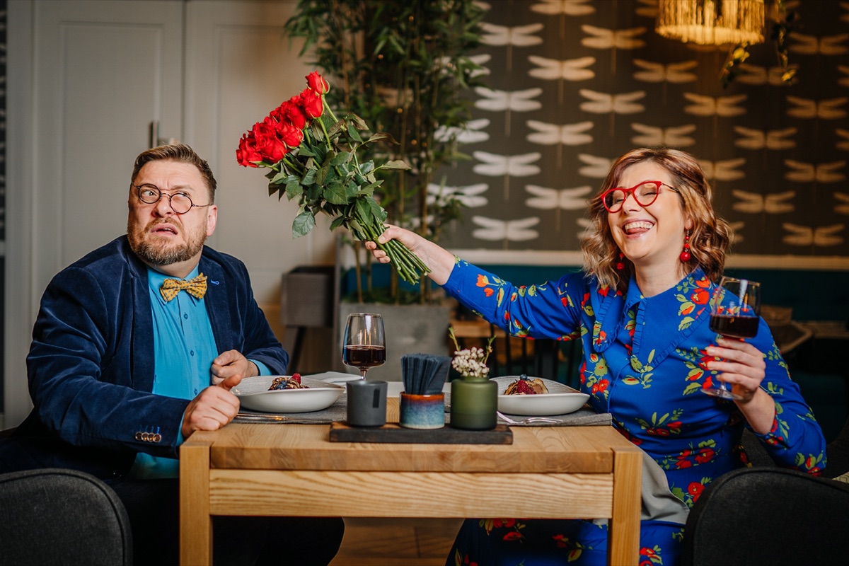 Quirky couple at a restaurant table with roses