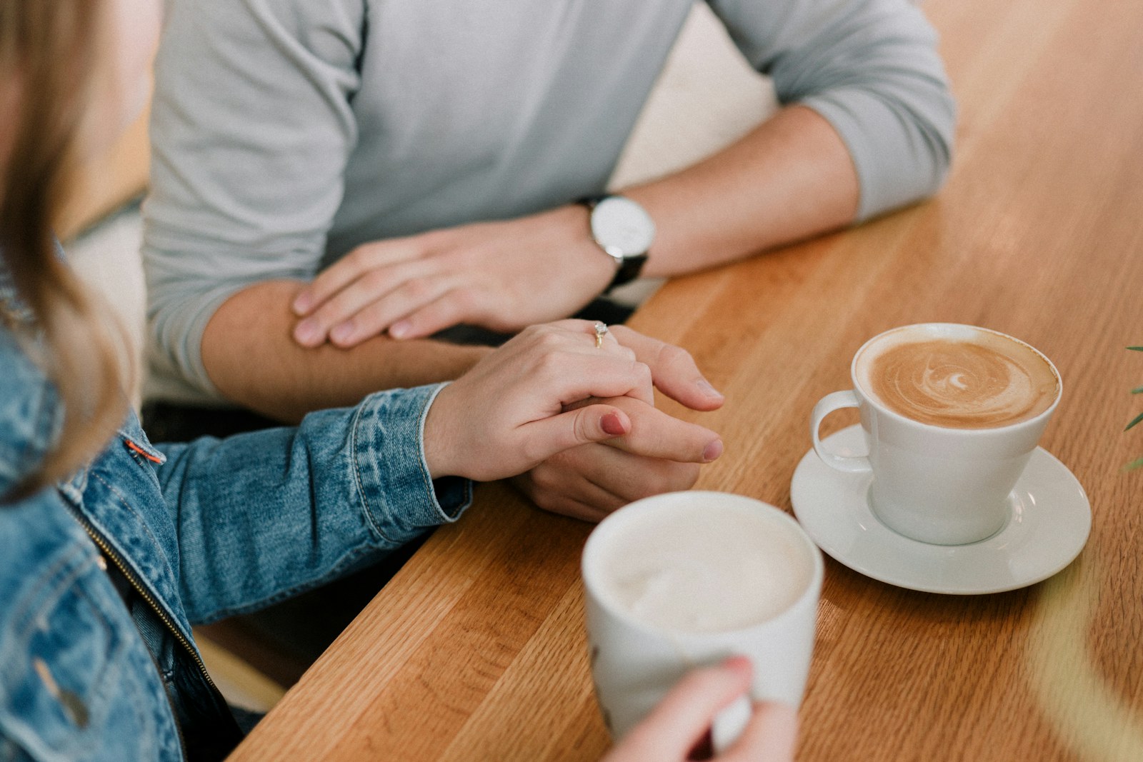 Couple holding hands over coffee on a first date