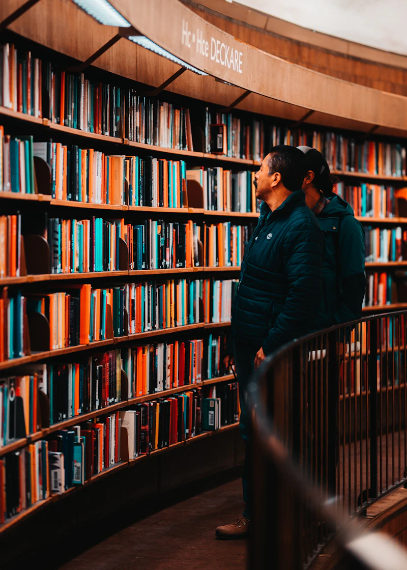Two people browsing shelves of colorful books together in a curved bookstore aisle