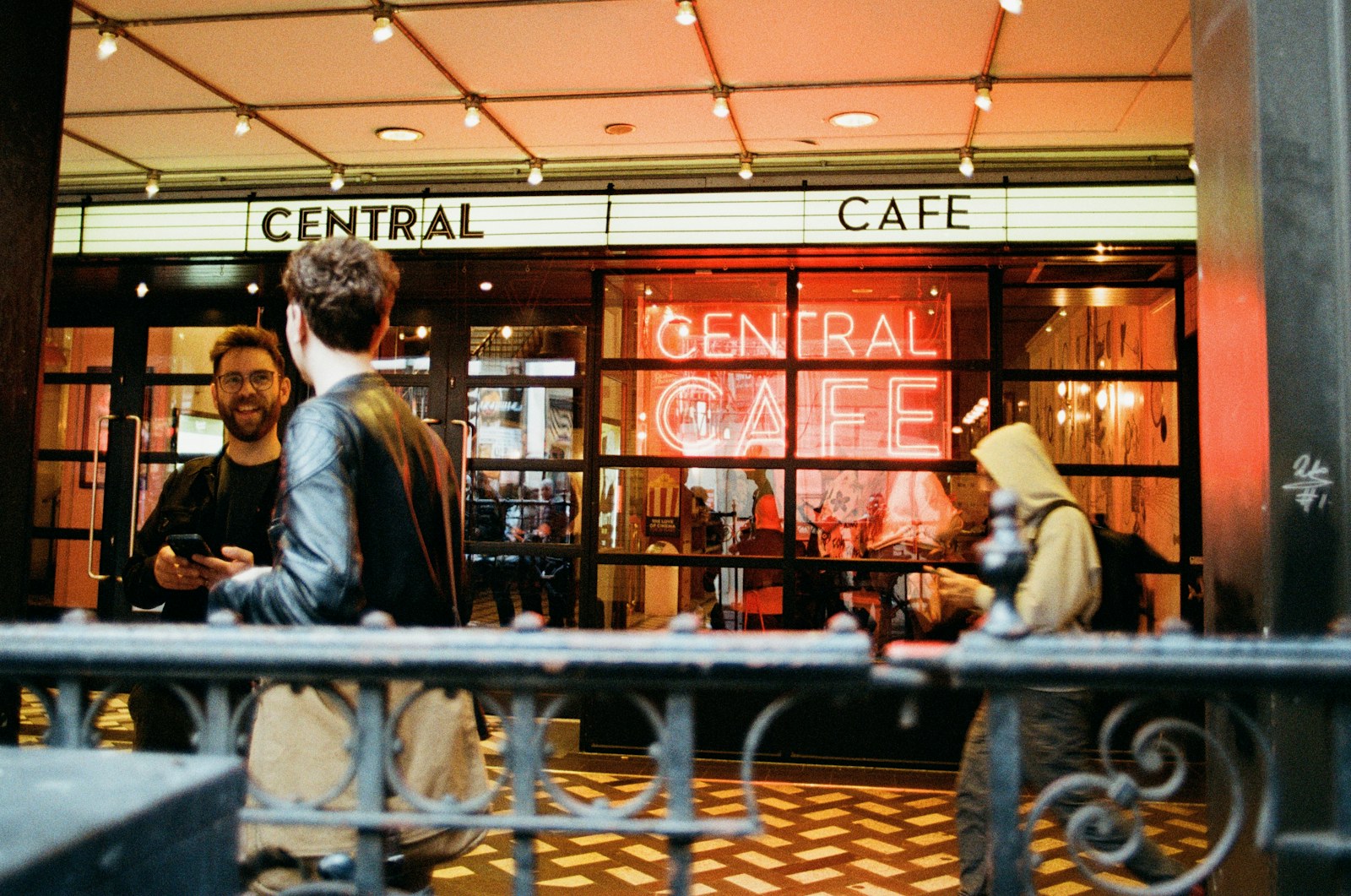 Two people talking outside a warmly lit cafe at night