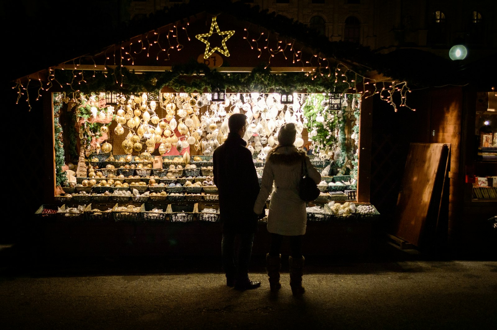 Couple browsing a Christmas market stall lit up at night